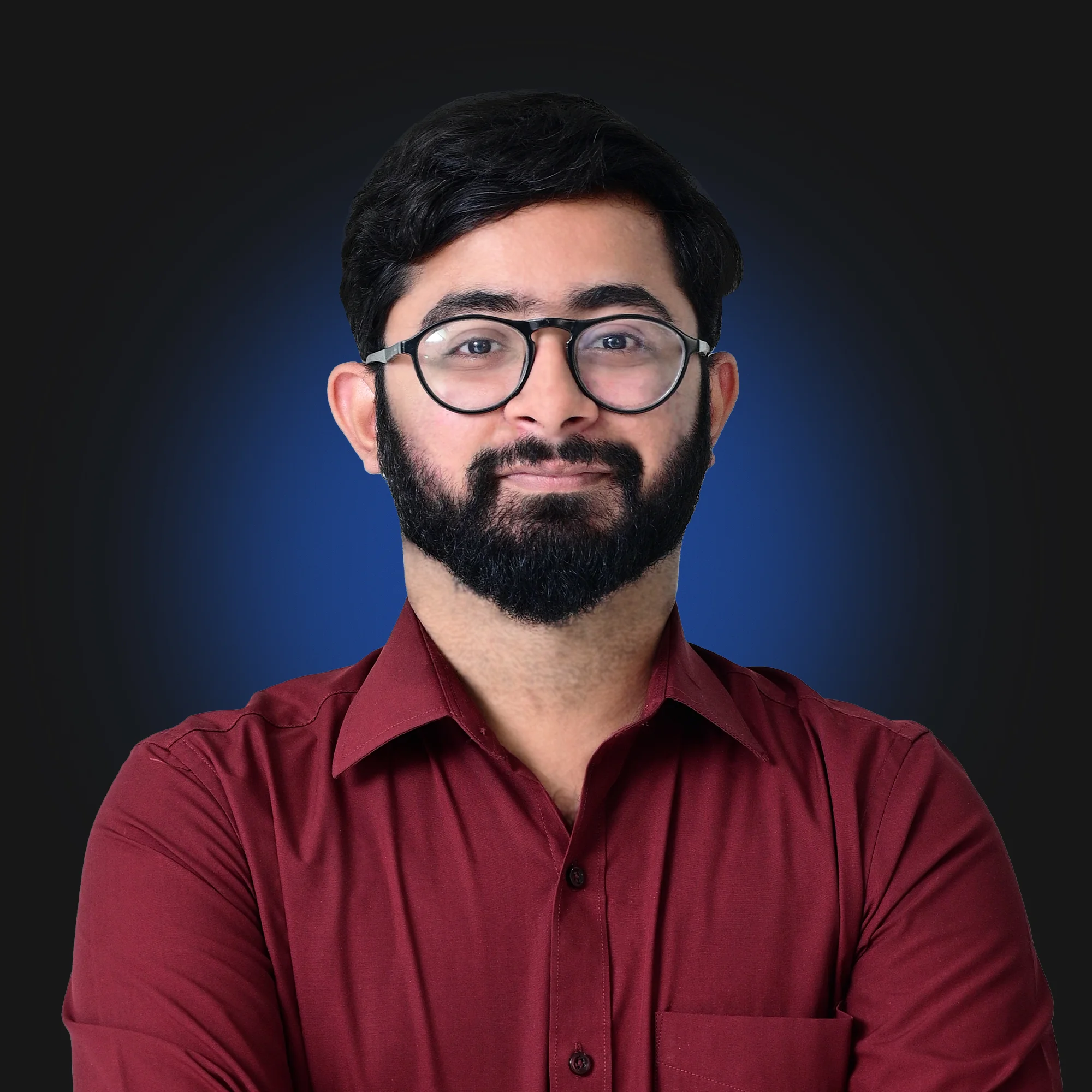 Man with beard and glasses wearing a maroon shirt against a dark background with blue halo.
