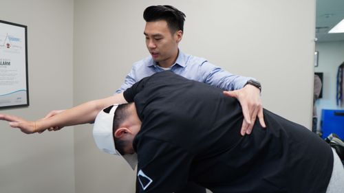Therapist assisting a patient in stretching their arm during a physical therapy session.