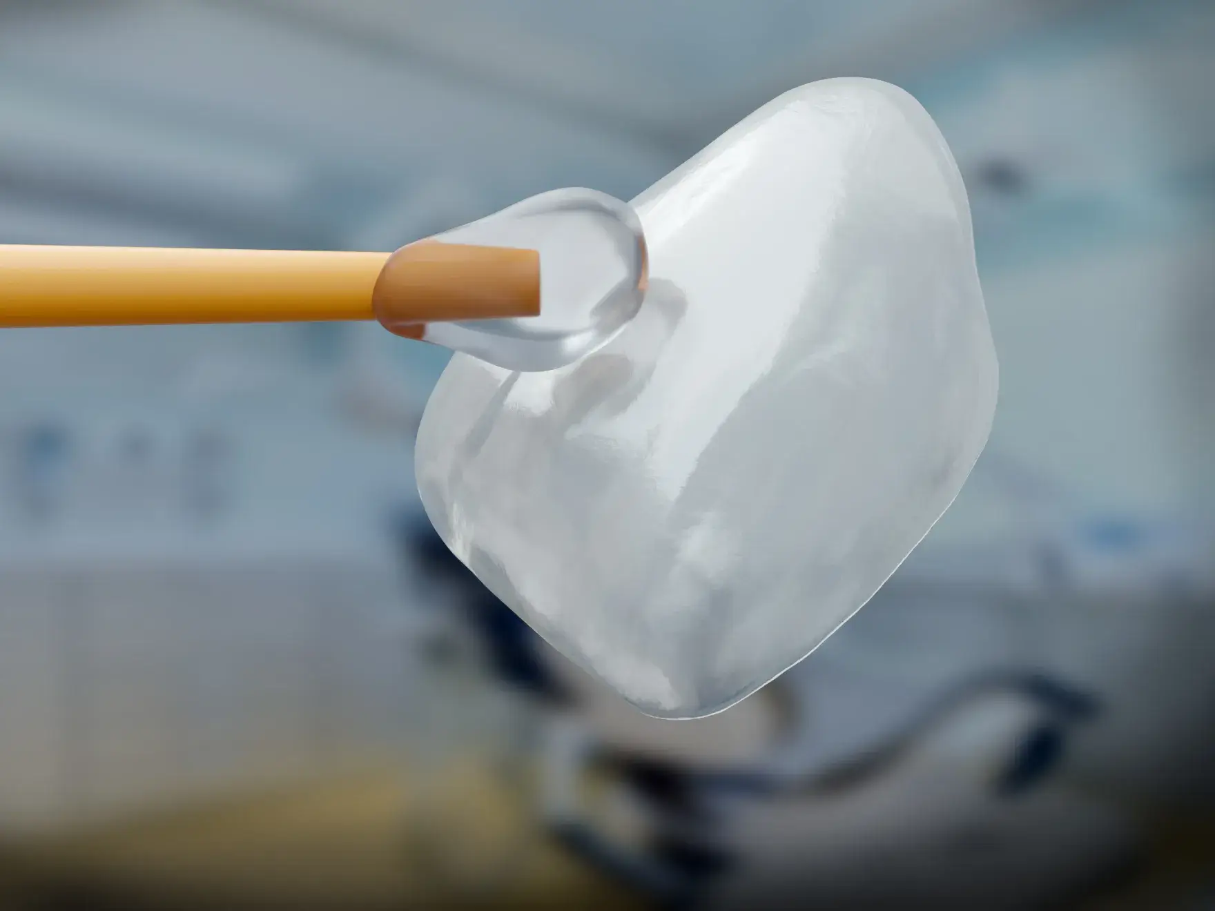 Clear dental veneer held by a tool in a blurred dental clinic background.