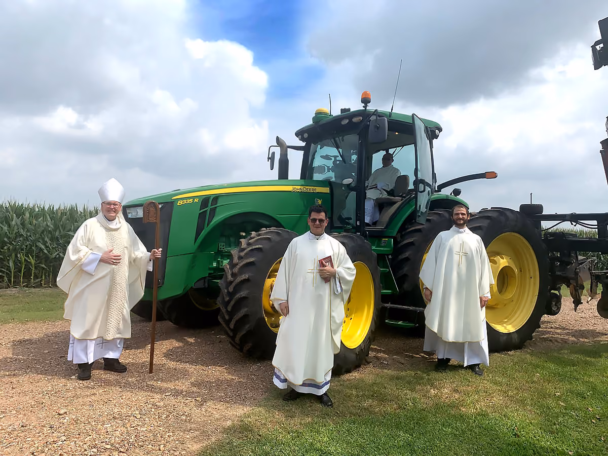 Bishop and priests posing with a tractor