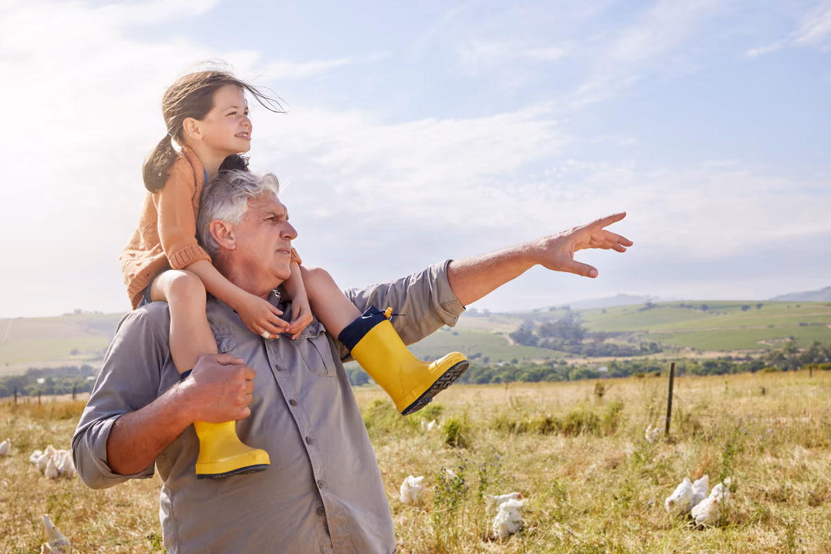 Man in a field with a little girl on his shoulders