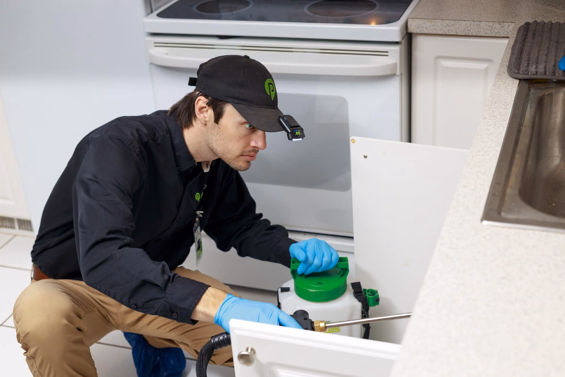 Technician applying interior pest control treatment in a Utah kitchen
