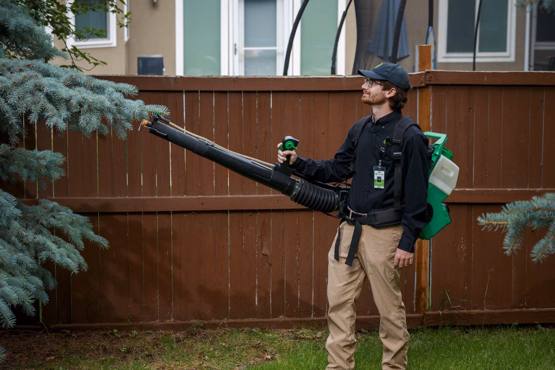 Pest Pro technician fogging trees and shrubs for mosquito control in a Utah yard