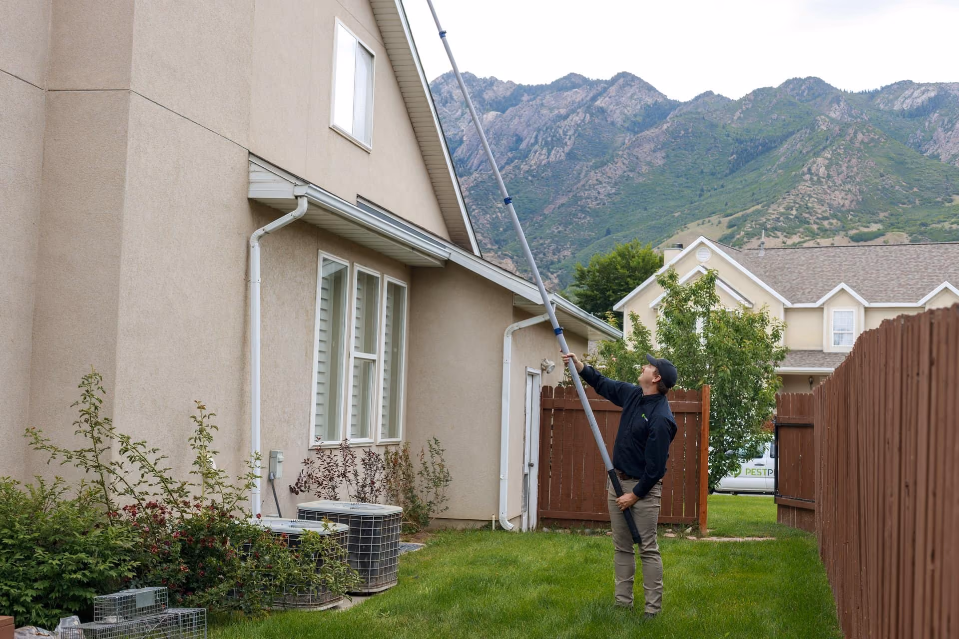 Technician treating a home exterior with an extension sprayer in Salt Lake City