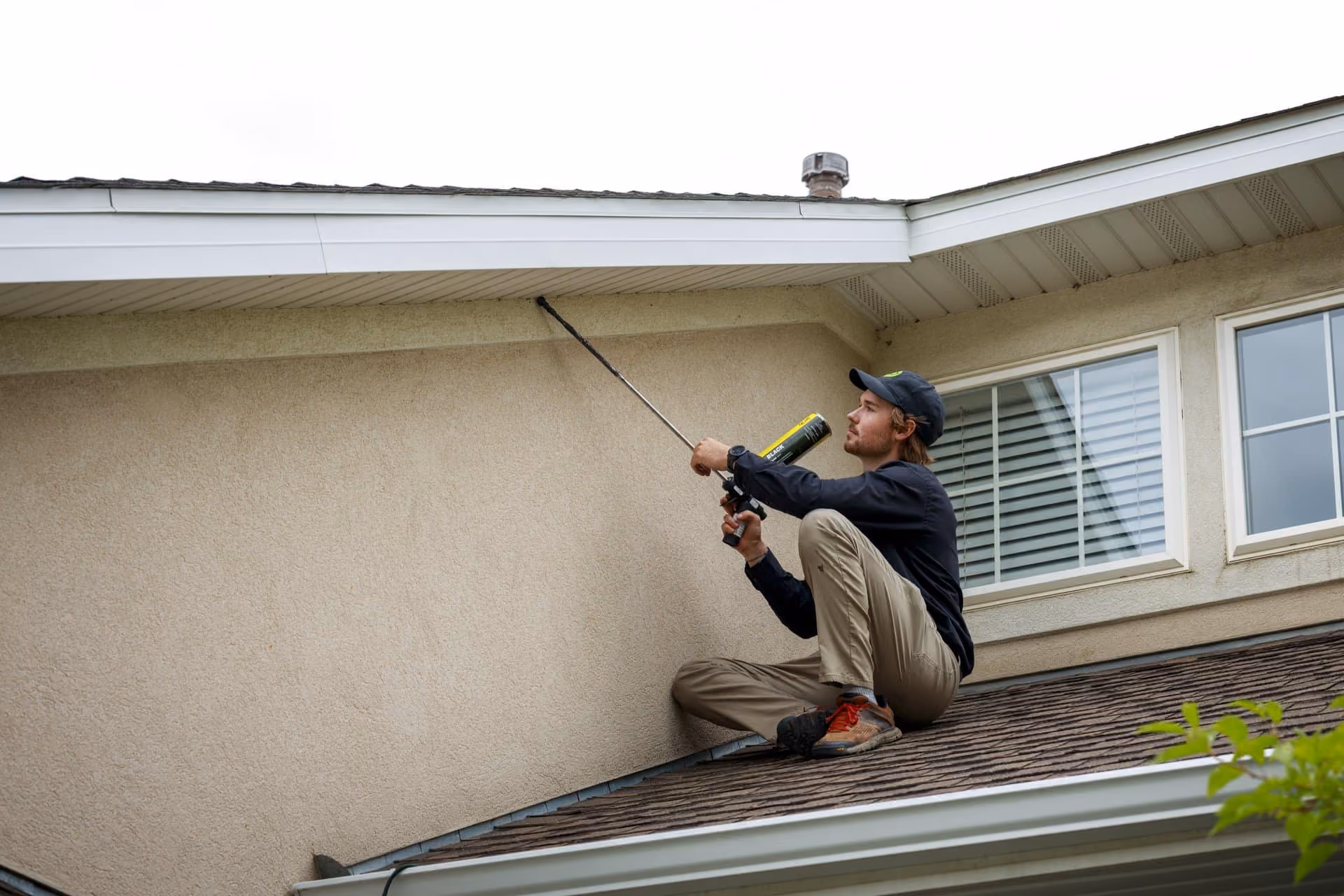 Technician treating a roofline for wasps and stinging insects in Utah