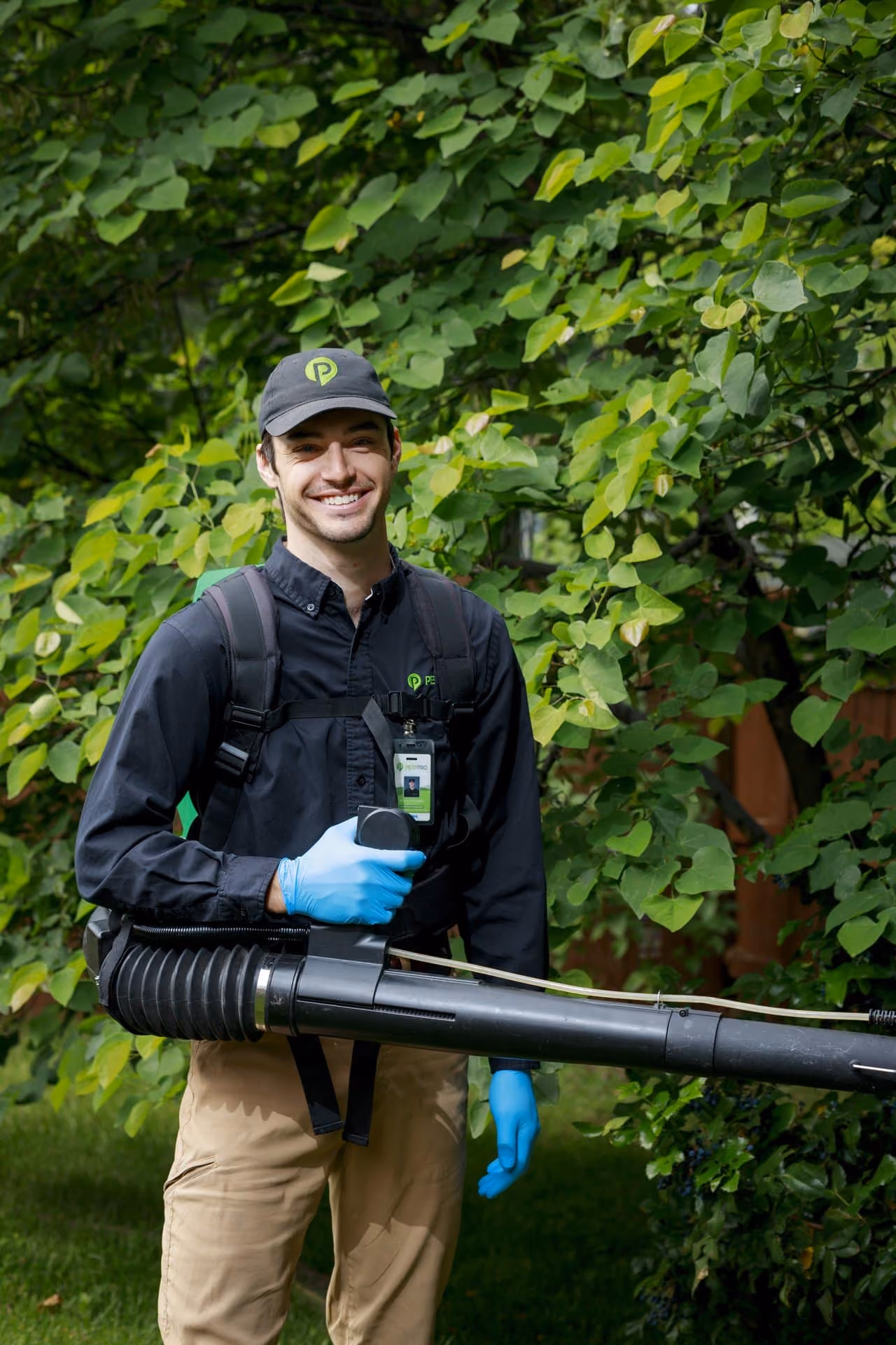 Friendly Pest Pro pest control technician holding equipment in a Utah backyard