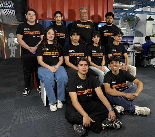 Grupo de diez personas que pertenecen a la tercera generación dora posando en un interior; la mayoría lleva camisetas negras de PowerBuilder; tres están sentadas delante, cuatro en el centro y tres de pie detrás.