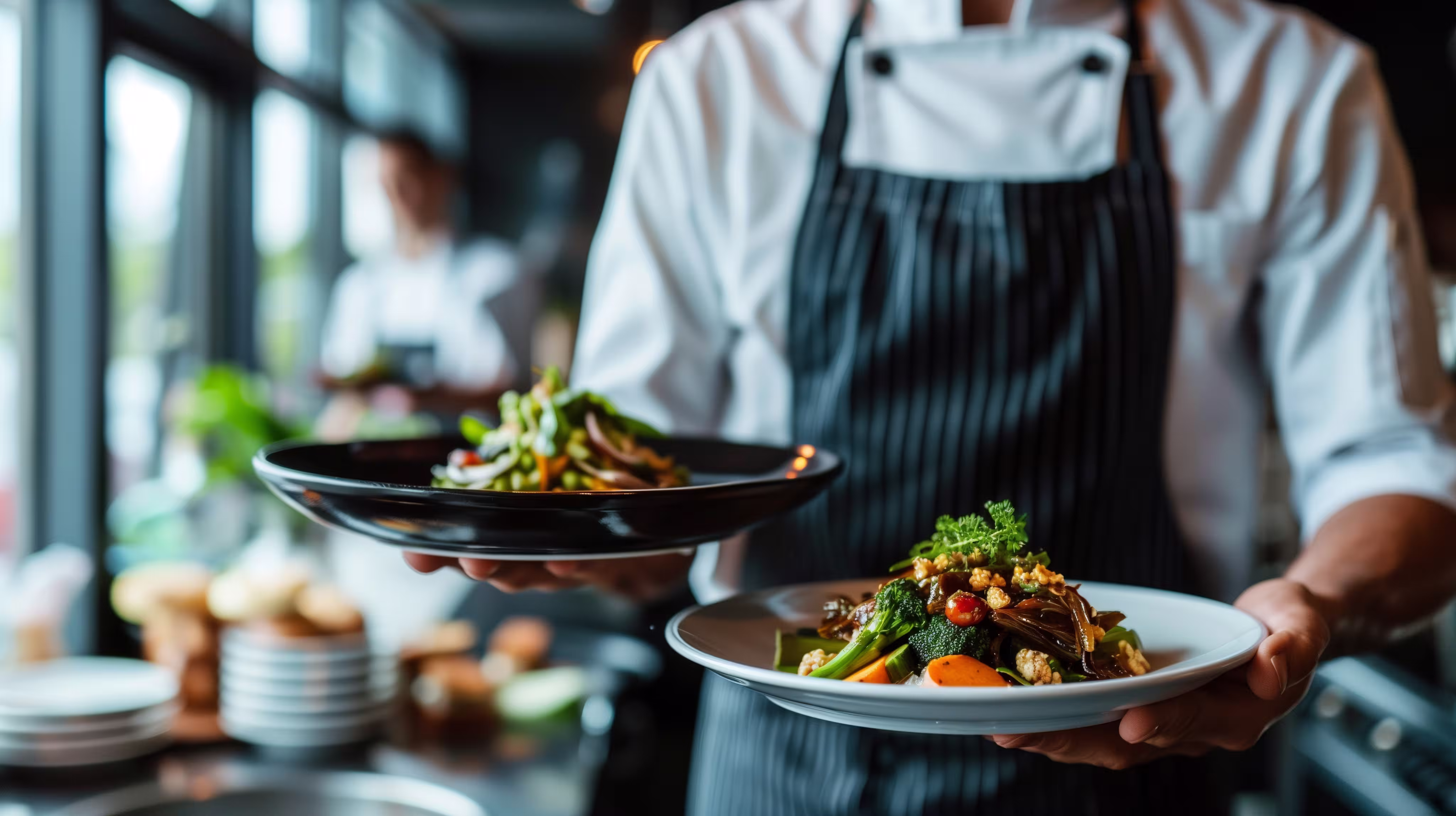 Chef carrying elegantly plated dishes at a private catering event in West Michigan