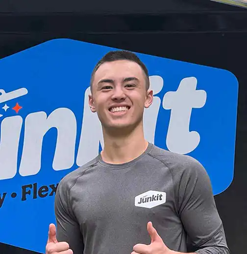 Miles Jordan, owner of Junkit, smiling in front of company truck in Charlotte Vermont