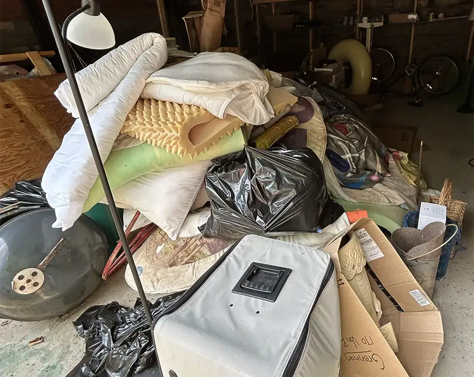 Cluttered garage with furniture and debris before realtor and tenant cleanout service in Vermont