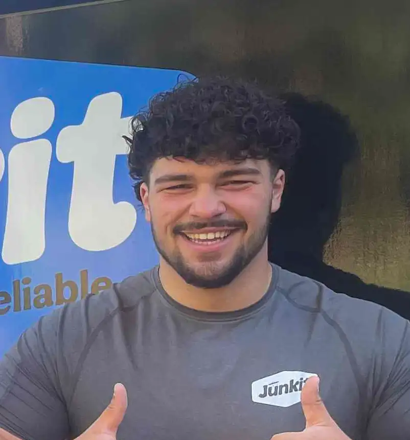 Miles Jordan, owner of Junkit, smiling in front of company truck in Charlotte Vermont
