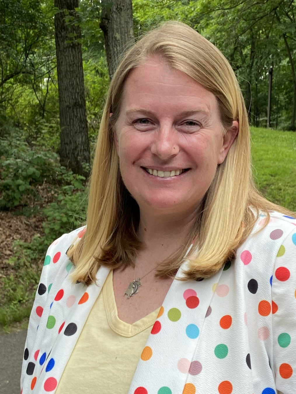 Jillian Fisher smiling outdoors in a colorful polka dot jacket