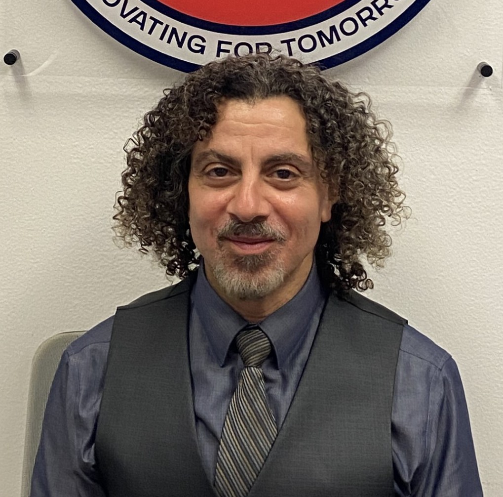 John Xavier staff portrait in front of school district logo