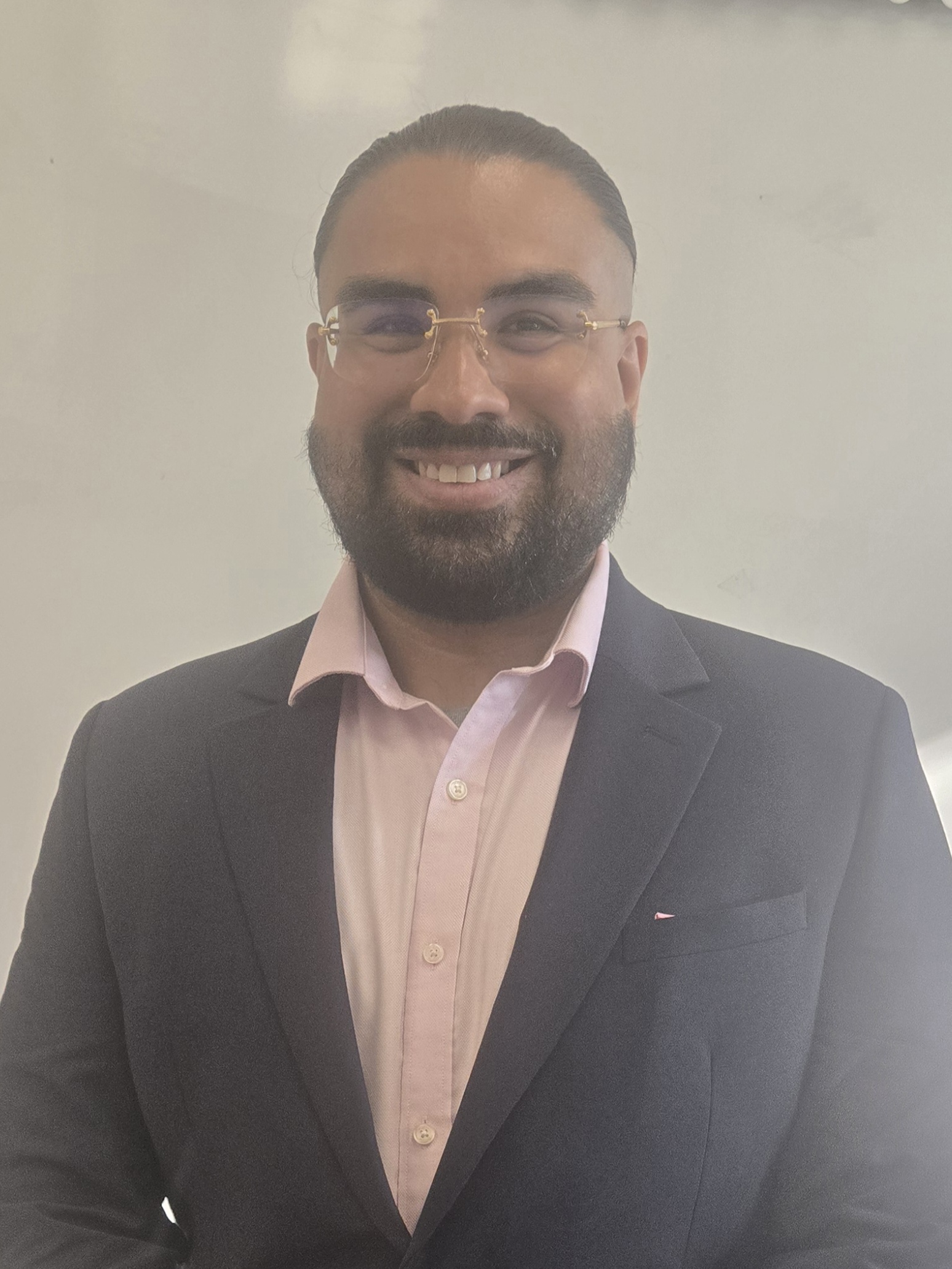 Juan Sierra smiling in a dark blazer and pink shirt