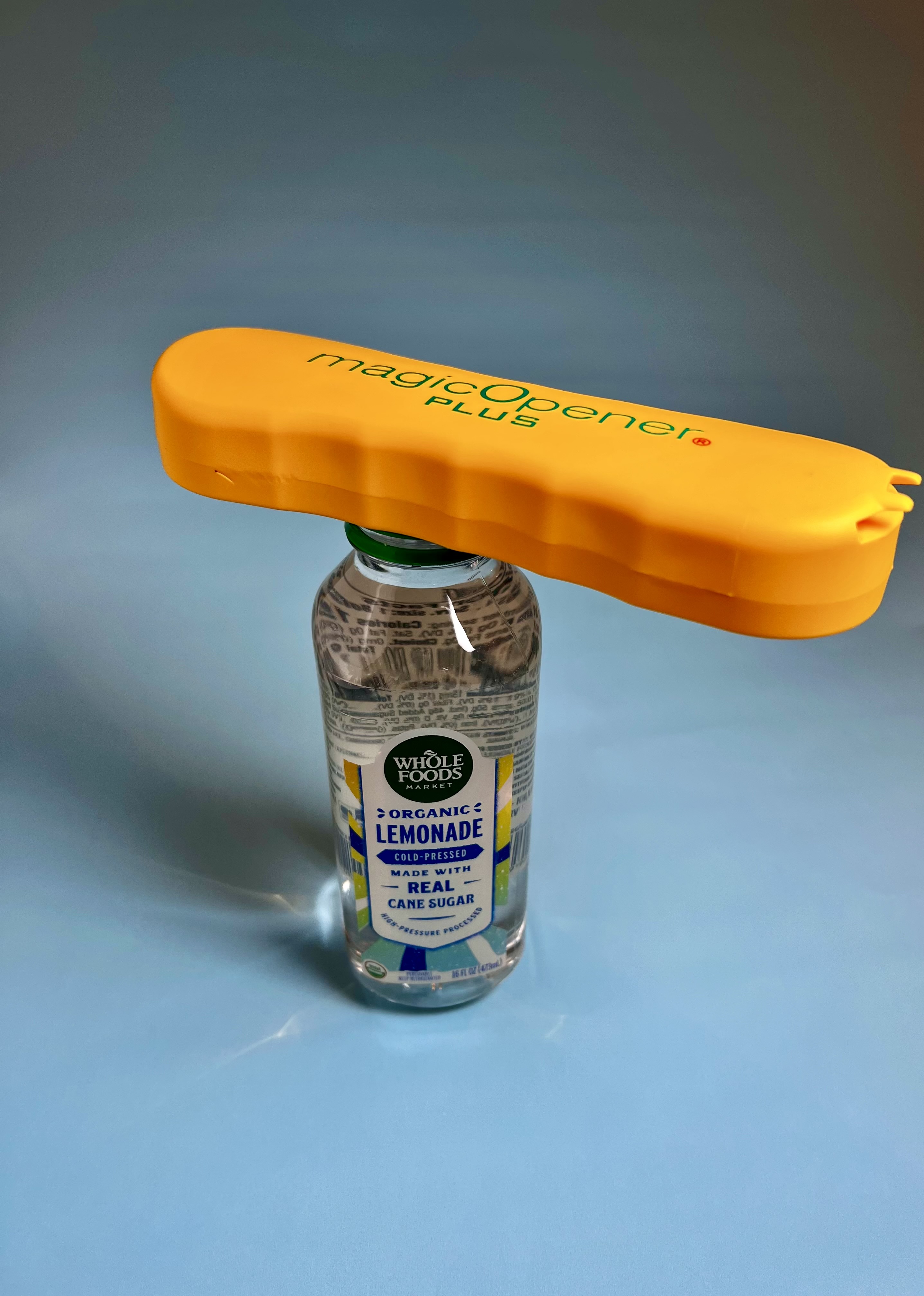 A water bottle is seen, on top of it is the magic opener with the lid inside it. 