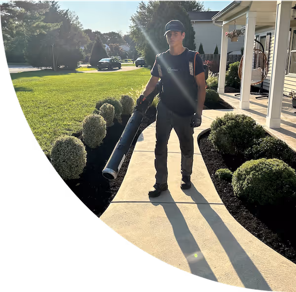 Lawn care professional using a leaf blower to clear path.