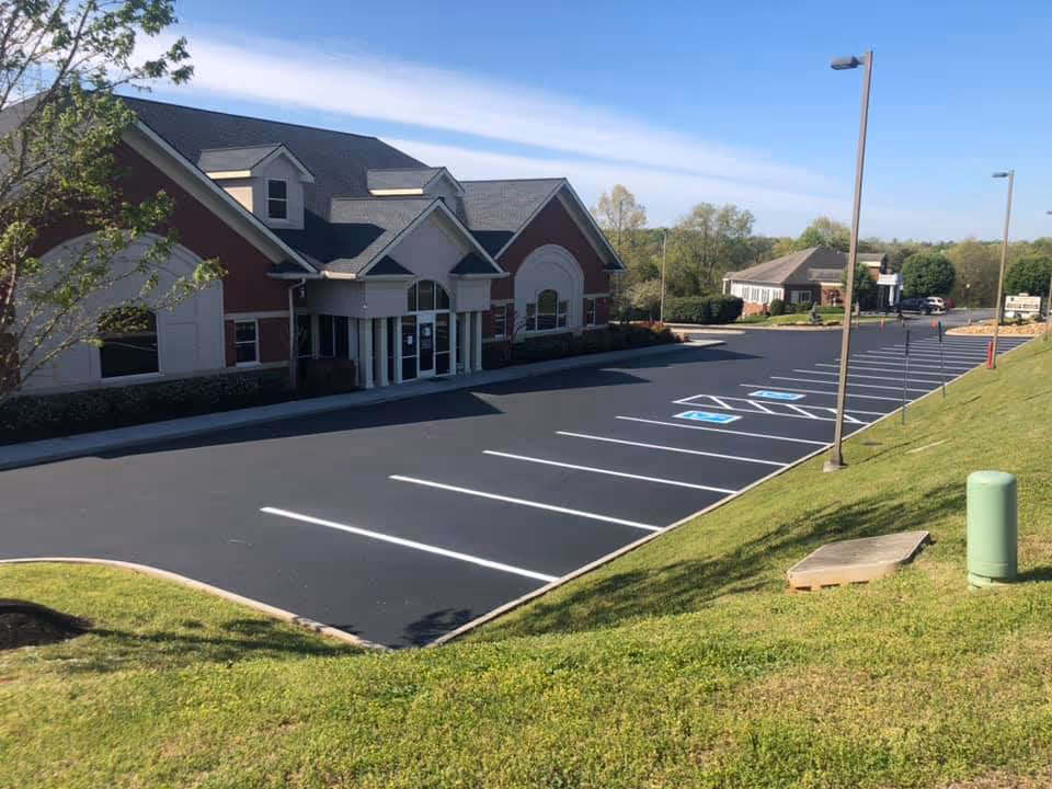 Empty parking lot with marked handicapped spaces next to a red brick building under a clear blue sky.
