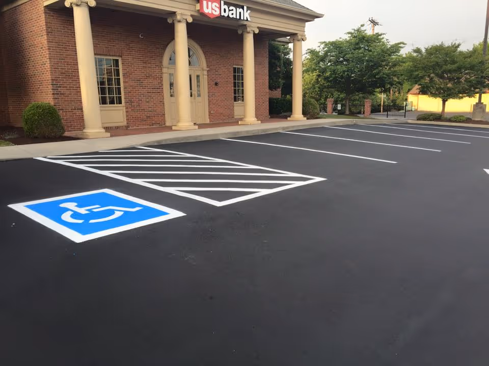 Empty parking lot in front of a US Bank building with a handicapped parking space marked by a blue and white symbol.