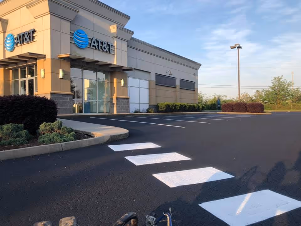 Empty parking lot with fresh white crosswalk lines leading to an AT&T store building on a clear day.