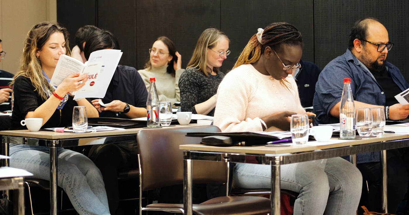 Participants lisant les livrets Créat