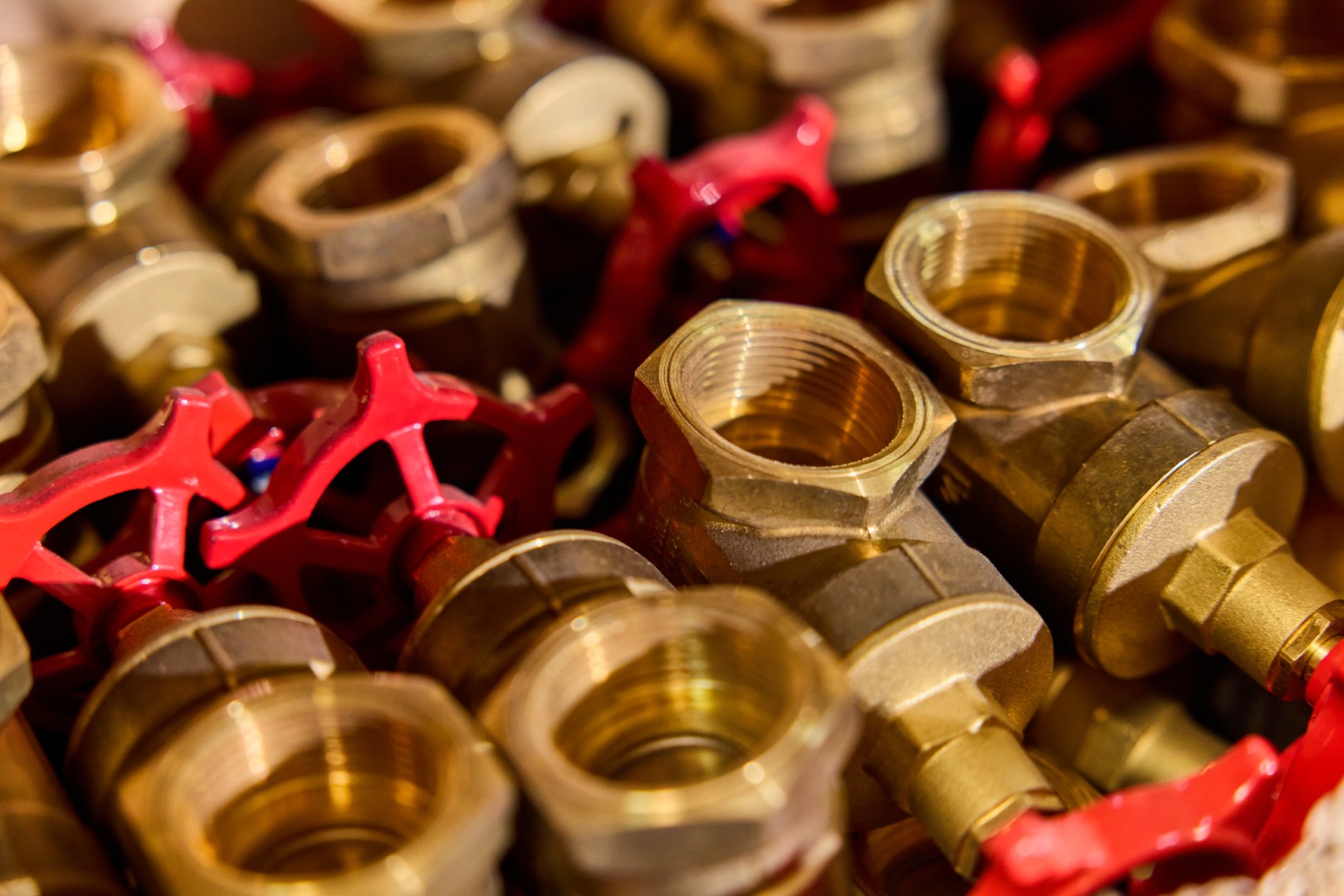 Close-up of brass water valves with red handles stacked together.