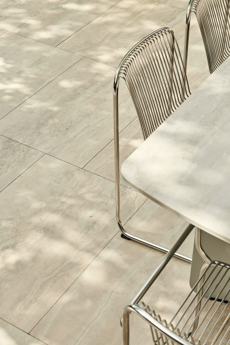 Tall tiered outdoor water feature with stacked stone column, cascading bowl tiers with LED lighting, surrounded by tropical bird of paradise, ferns, and red flowering plants against a wood fence at night.