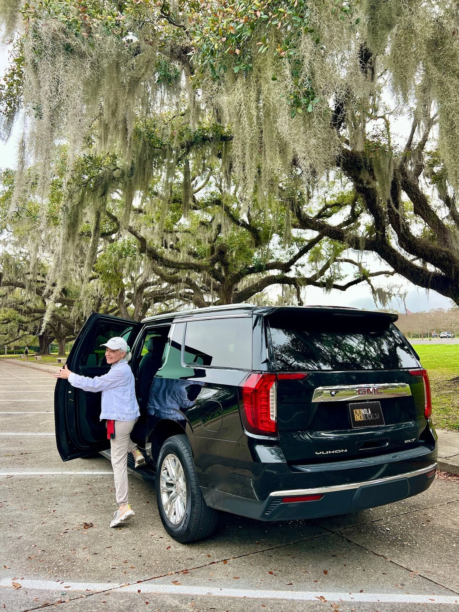 Passenger at the open rear door of a black SUV in City Park, New Orleans