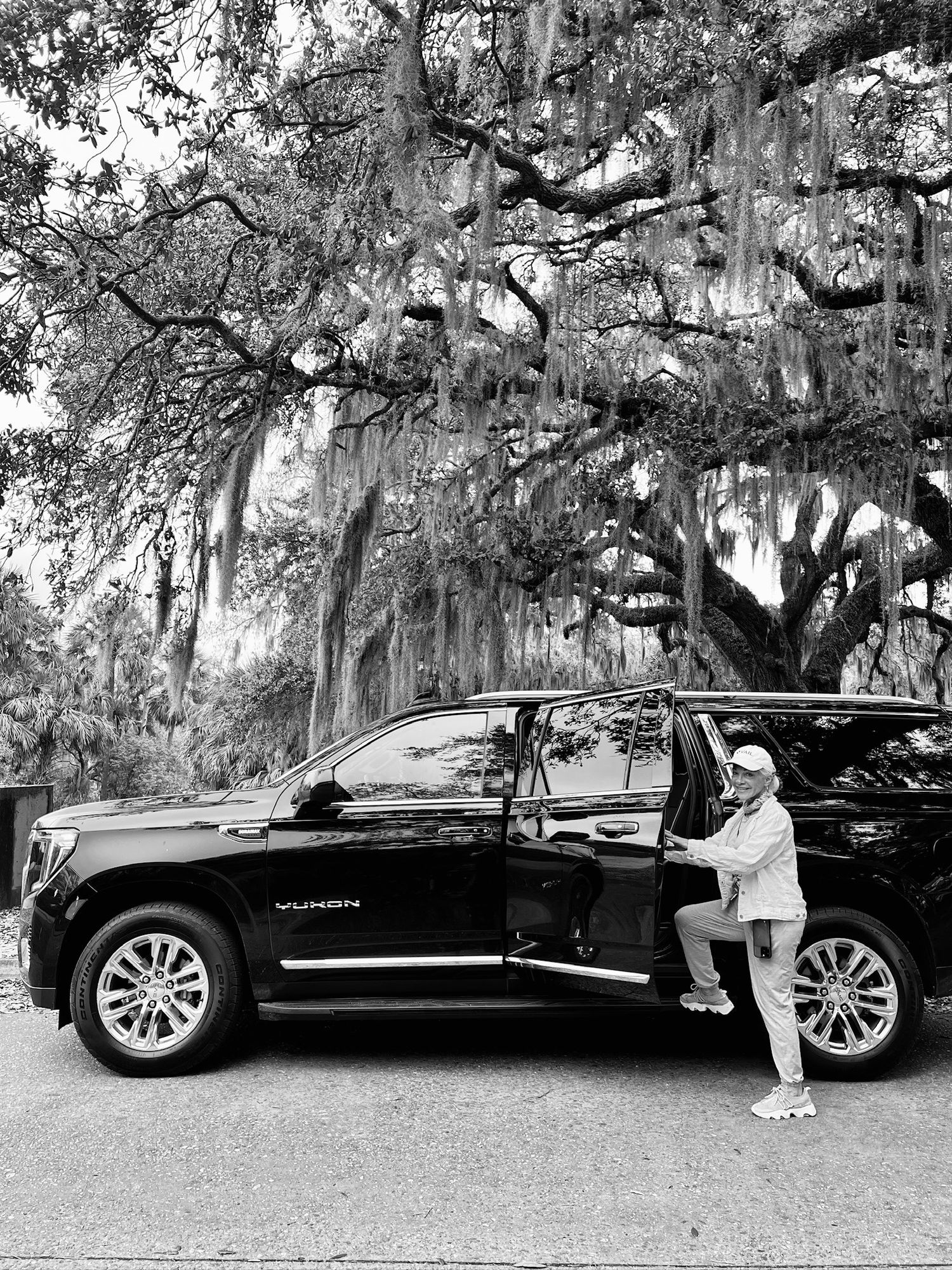 Black and white photo of a passenger entering a black SUV in City Park