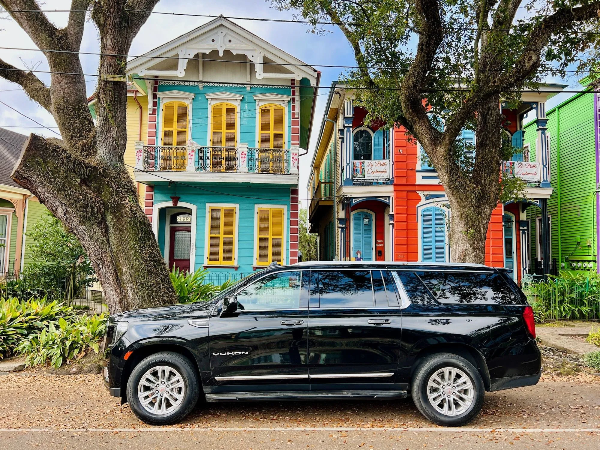 Black SUV in front of colorful New Orleans shotgun houses