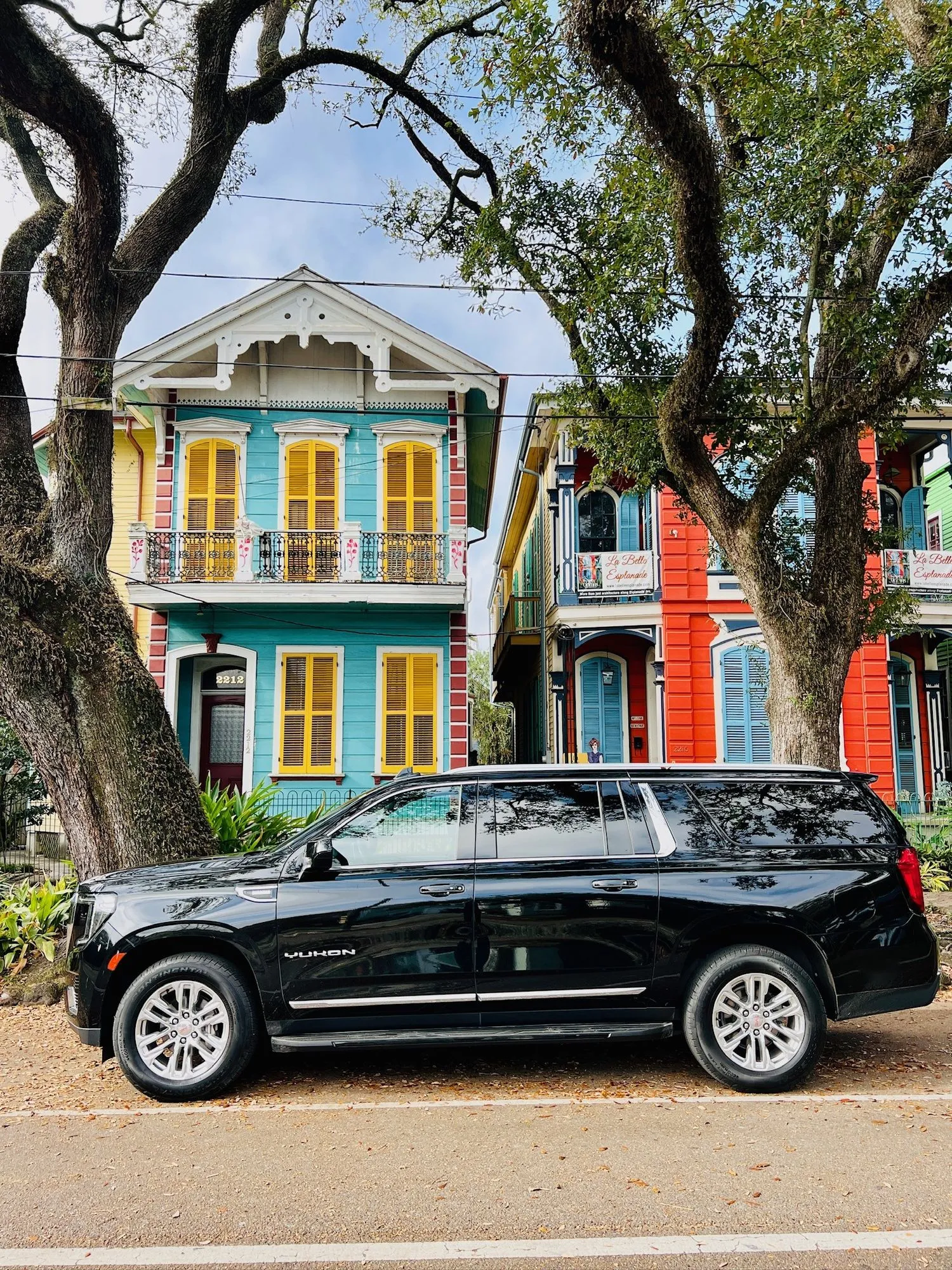 Black SUV in front of colorful New Orleans shotgun houses