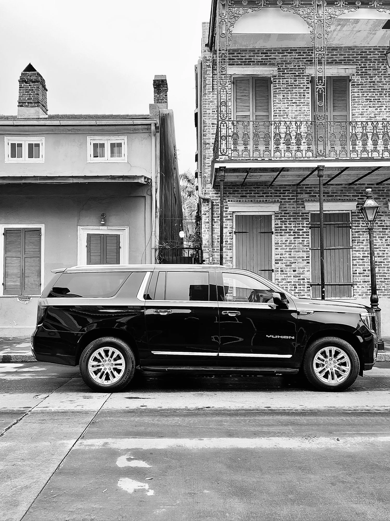 Black and white photo of a black SUV on a French Quarter street