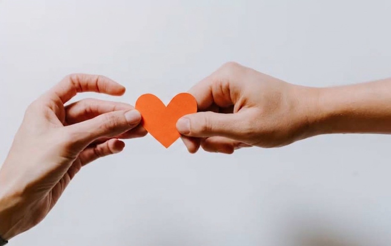 deux mains qui tiennent un coeur comme symbole d'attachement. Illium l'application de l'amour pour les célibataires et les couples.