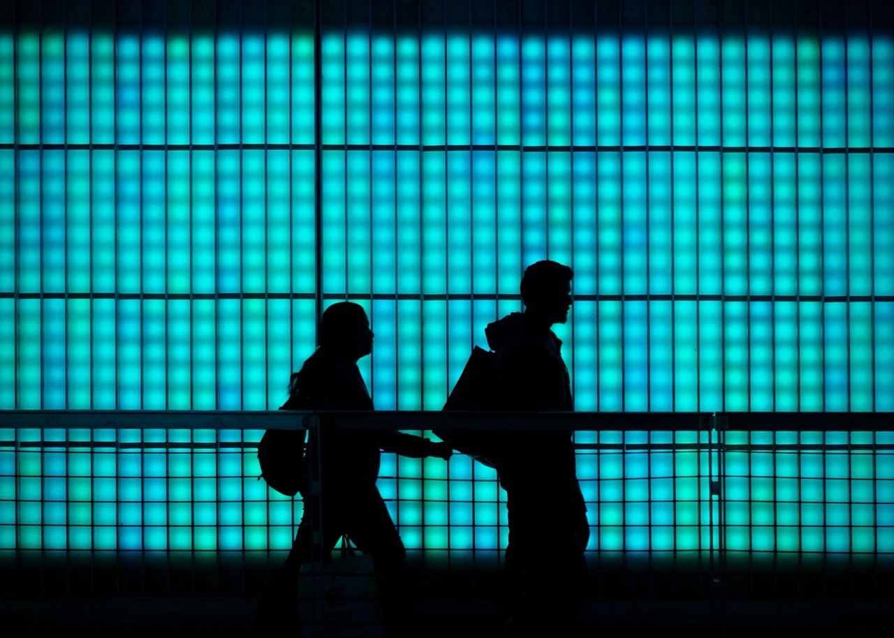2 personnes qui marchent dans la rue en contre lumiere avec un fond bleu derrire. Illium l'application de l'amour pour les célibataires et les couples.