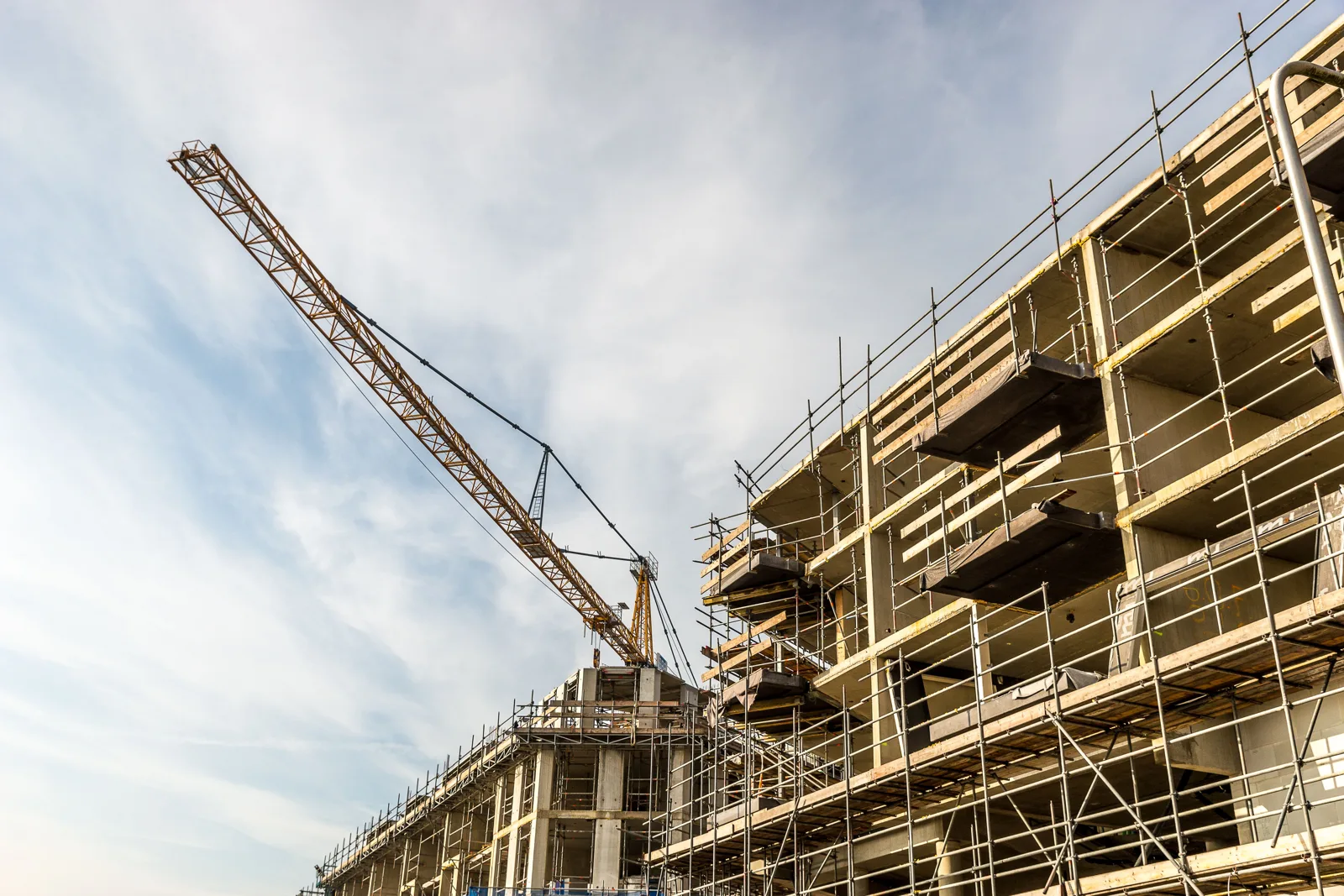 Tower crane over a mid-rise building wrapped in scaffolding