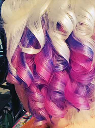 Blonde hair styled in tight curls with purple and pink color accents.