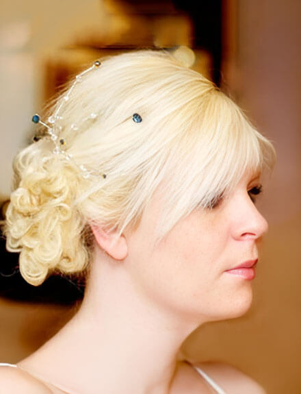 Profile of a woman with blonde hair styled in an updo adorned with delicate decorative pins.