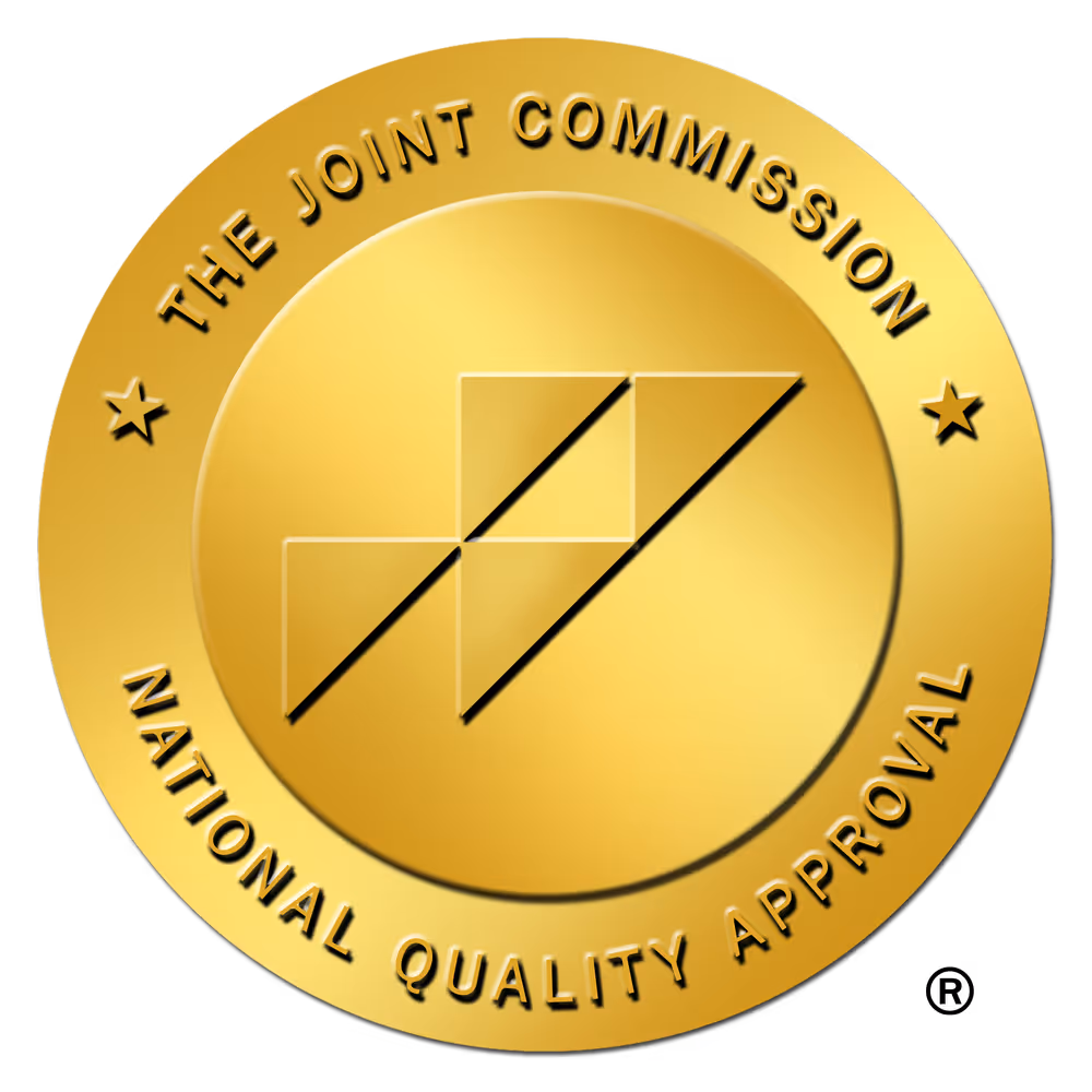 Gold circular emblem with The Joint Commission National Quality Approval text and a stylized intersecting check mark design in the center.