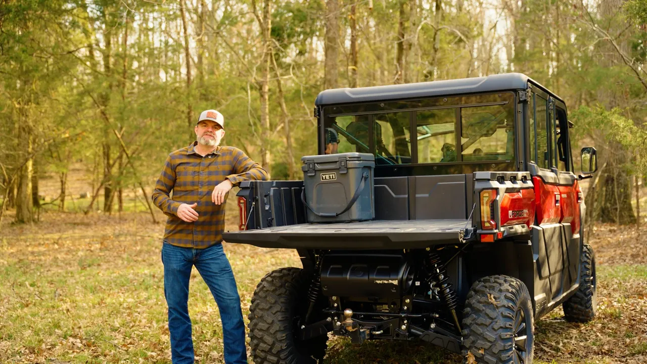 Paul Morrsion in plaid shirt and cap leaning on an off-road vehicle with a Yeti cooler in the bed.