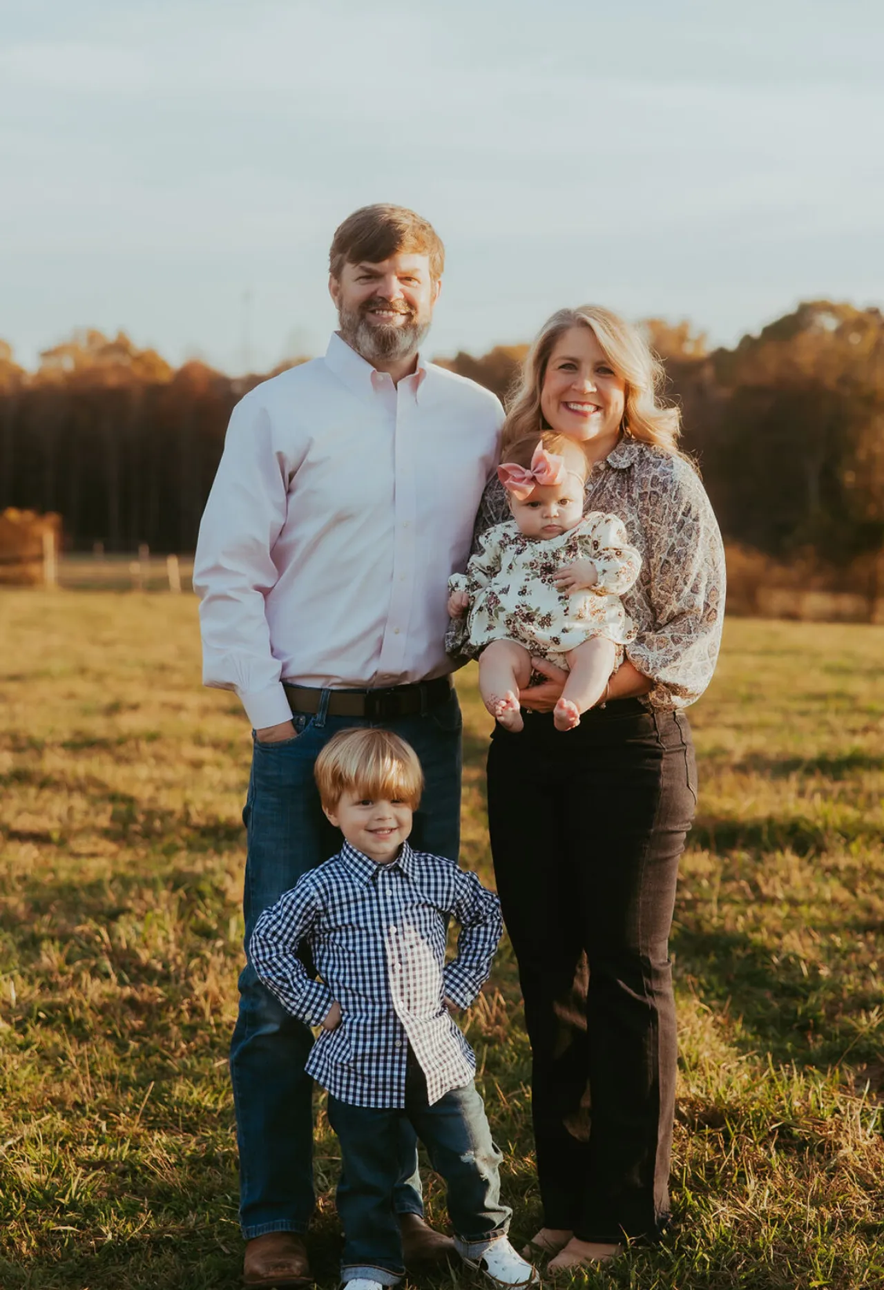 Paul Morrison's family of four outdoors: father, mother holding baby girl, and young boy in a grassy field.