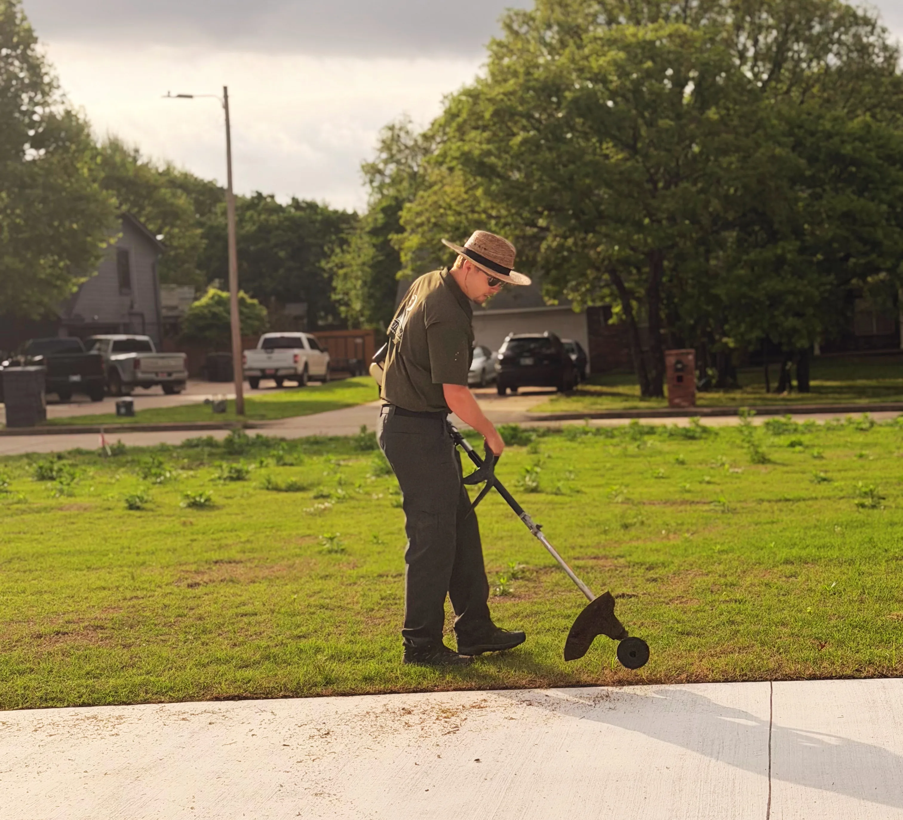 Mason Richardson string trimming a lawn edge along a sidewalk