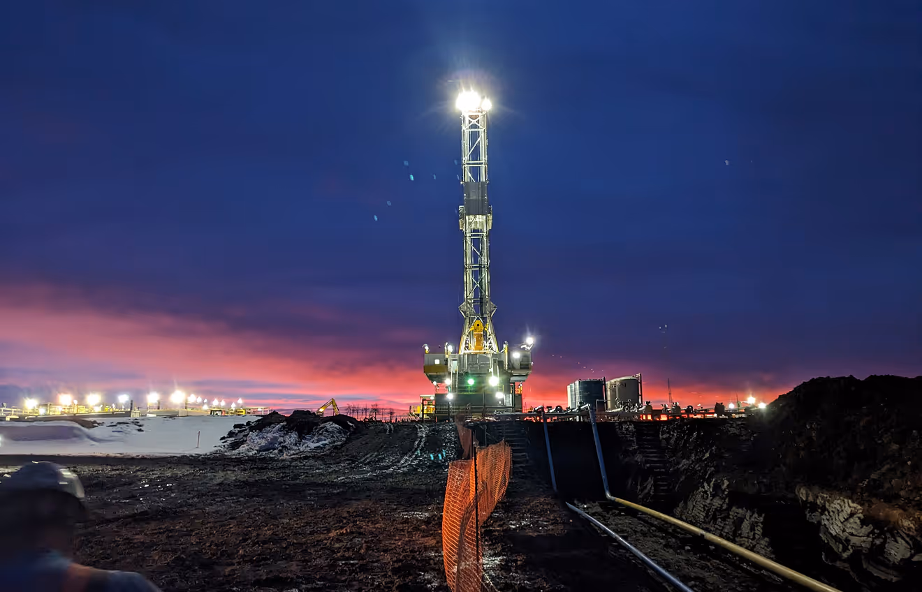 A crane on an industrial project site at sunset.