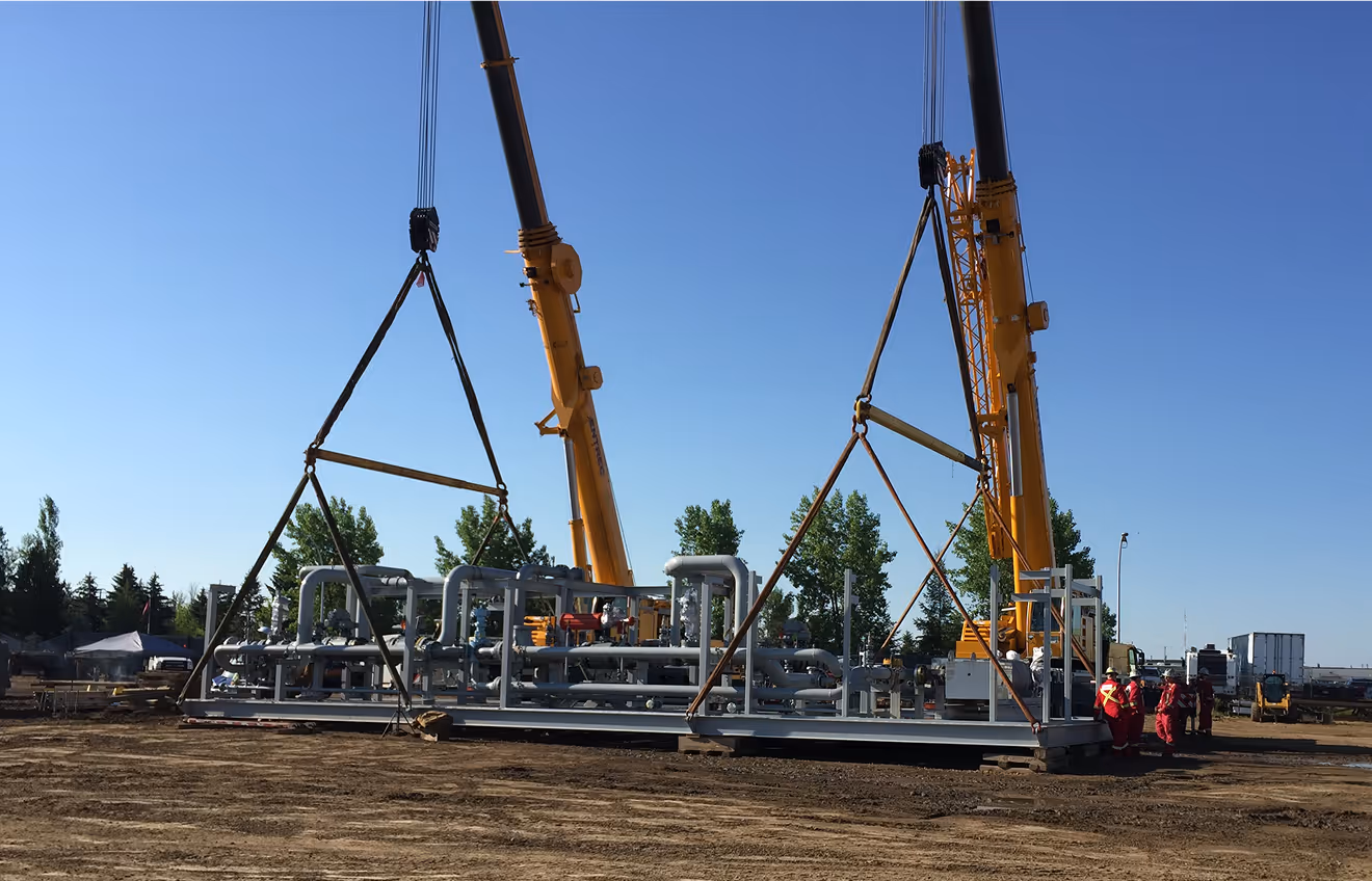 Two large cranes hoisting industrial infrastructure on a remote site.