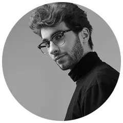 Black and white portrait of a young man with glasses and a beard wearing a black turtleneck.