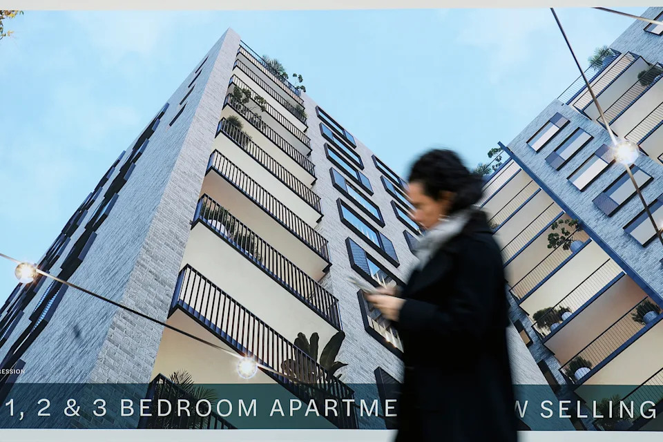 A woman walks past an apartment advertisement.