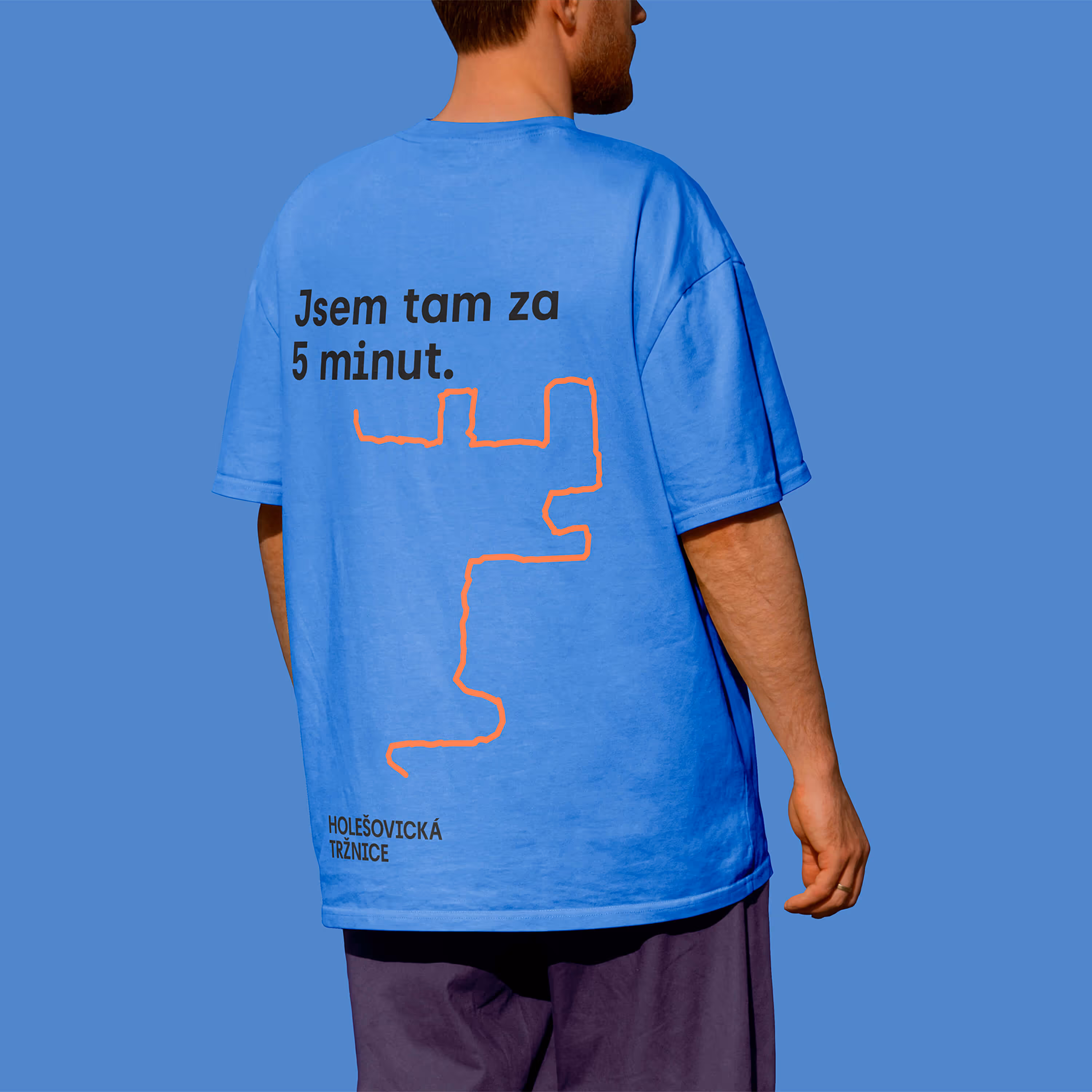 Muž zobrazený zezadu v modrém tričku s nápisem 'Jsem tam za 5 minut' a červenou linkou.