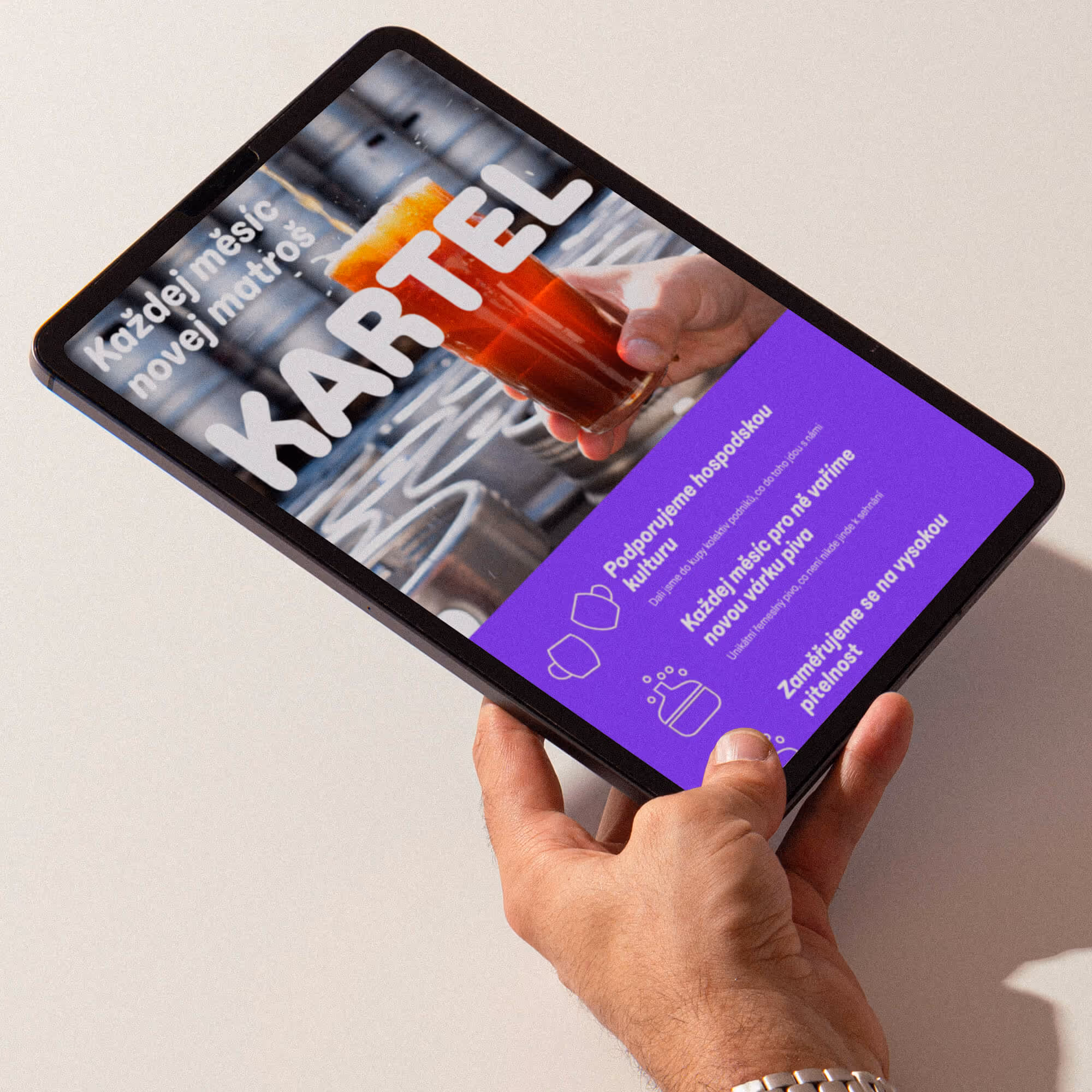Ruka drží tablet zobrazující reklamu na pivní kartel s červeným pivem a textem v češtině.