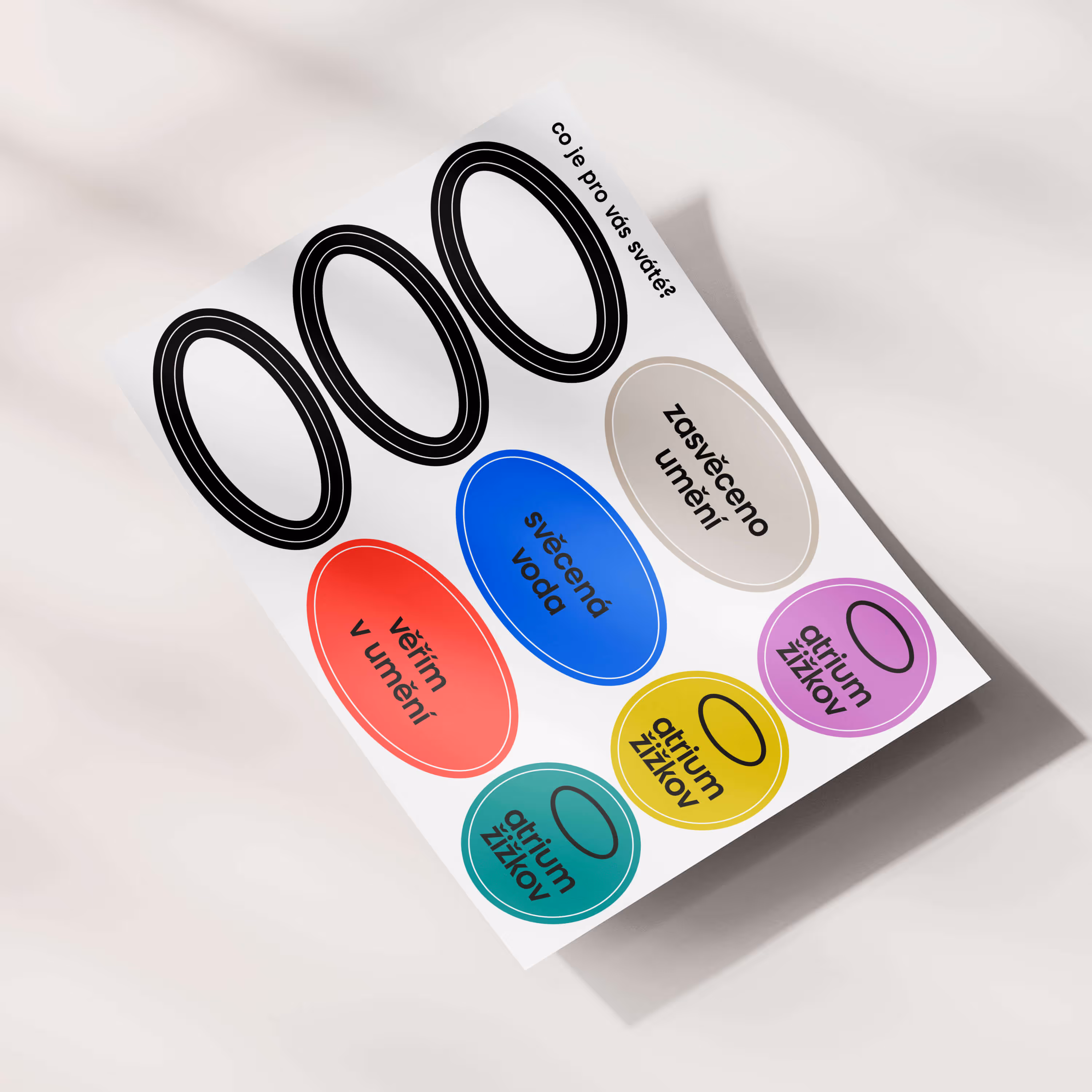 List of oval name tags in various colors with Czech text about holy water and art dedication.