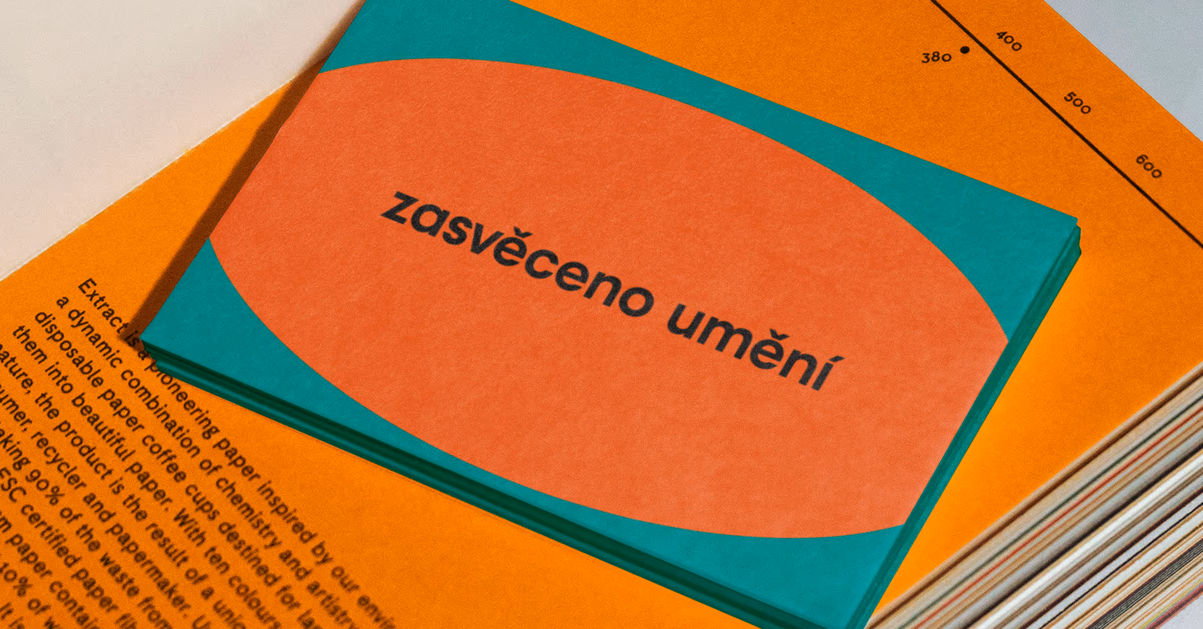 Kniha s barevným obalem a nápisem 'zasvěceno umění' položená na oranžovém textu.