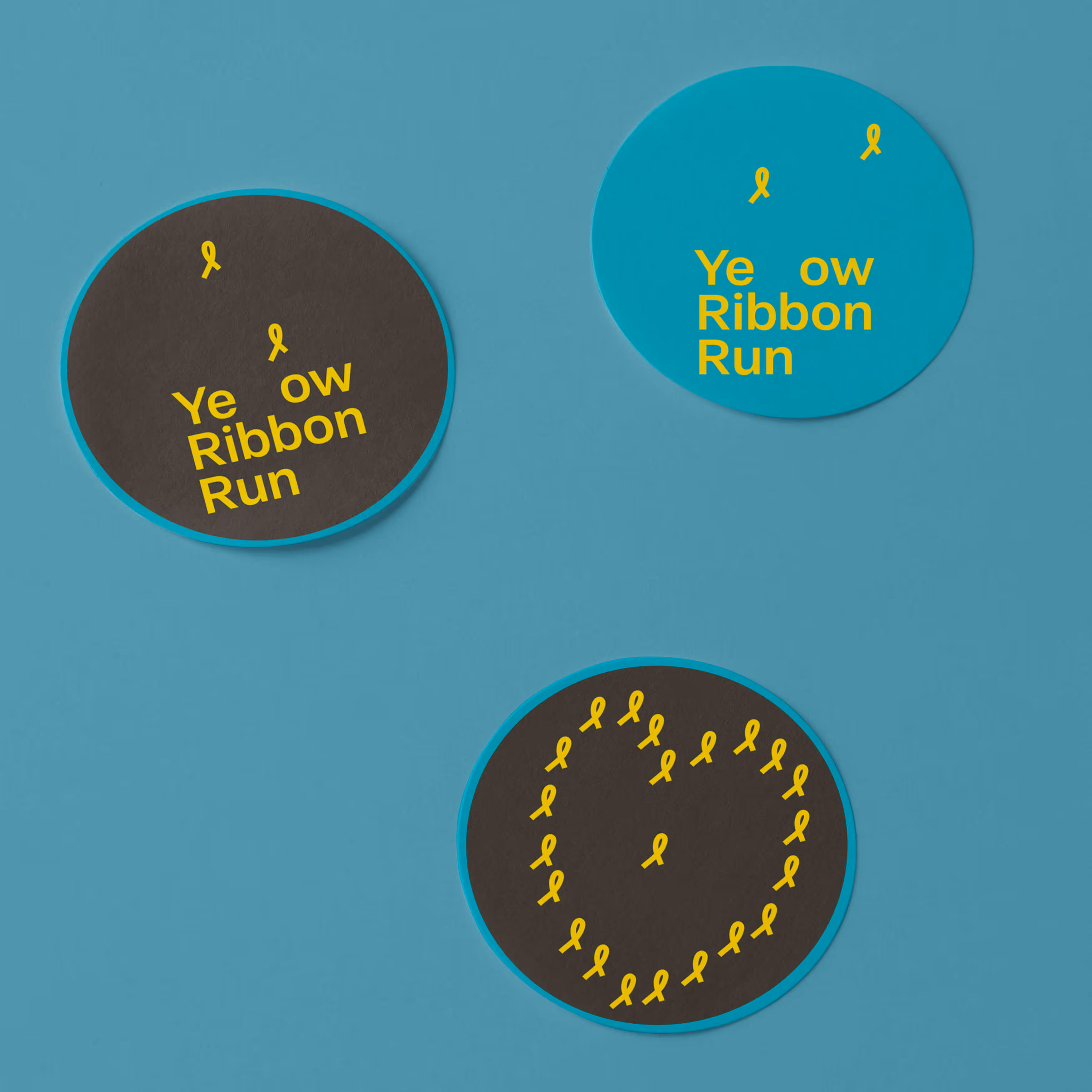 Tři modré a černé kruhové nálepky s žlutými stuhami a nápisem Yellow Ribbon Run.