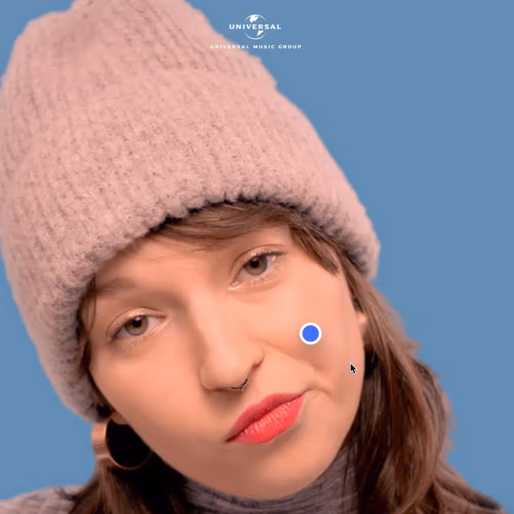 Žena s čepicí a náušnicemi, s červenými rty, na modrém pozadí.